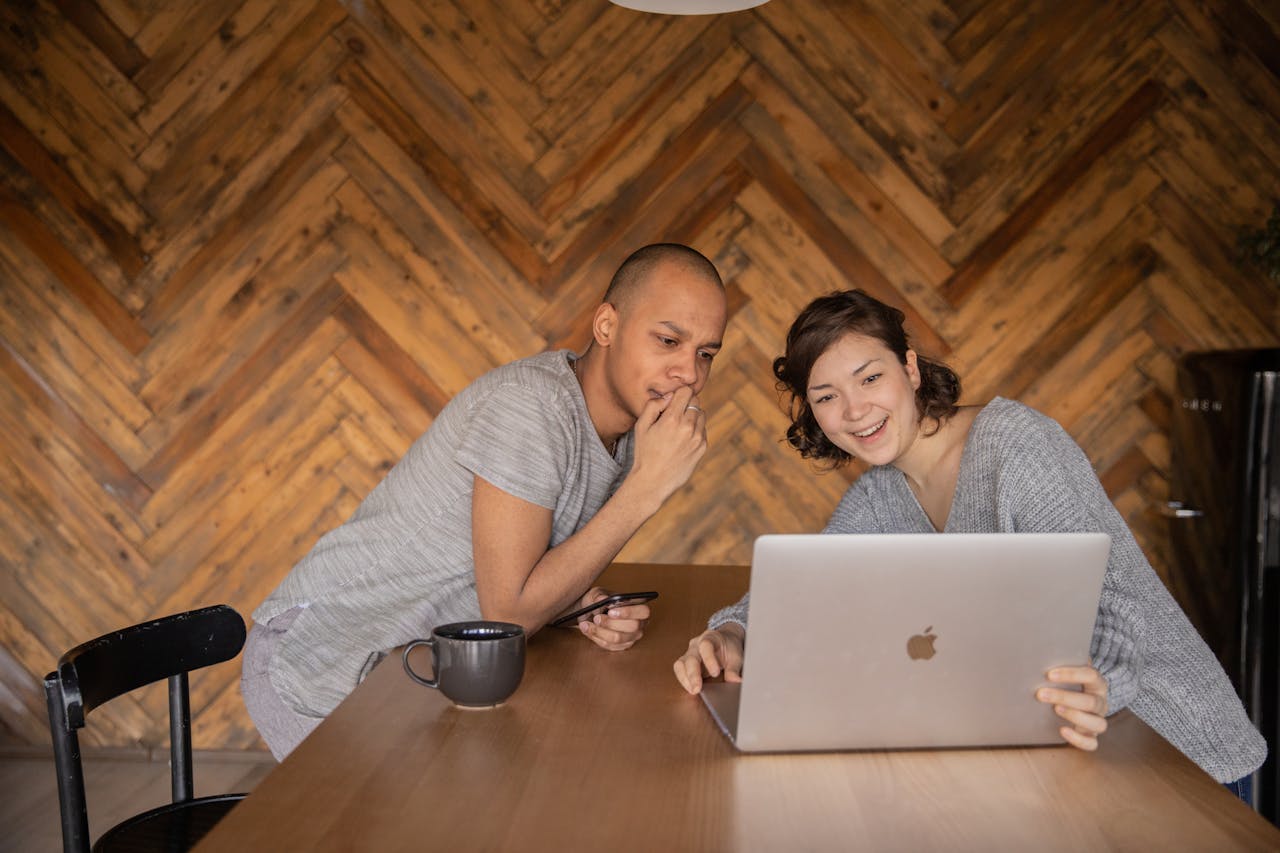 Cheerful friends watching video on laptop together